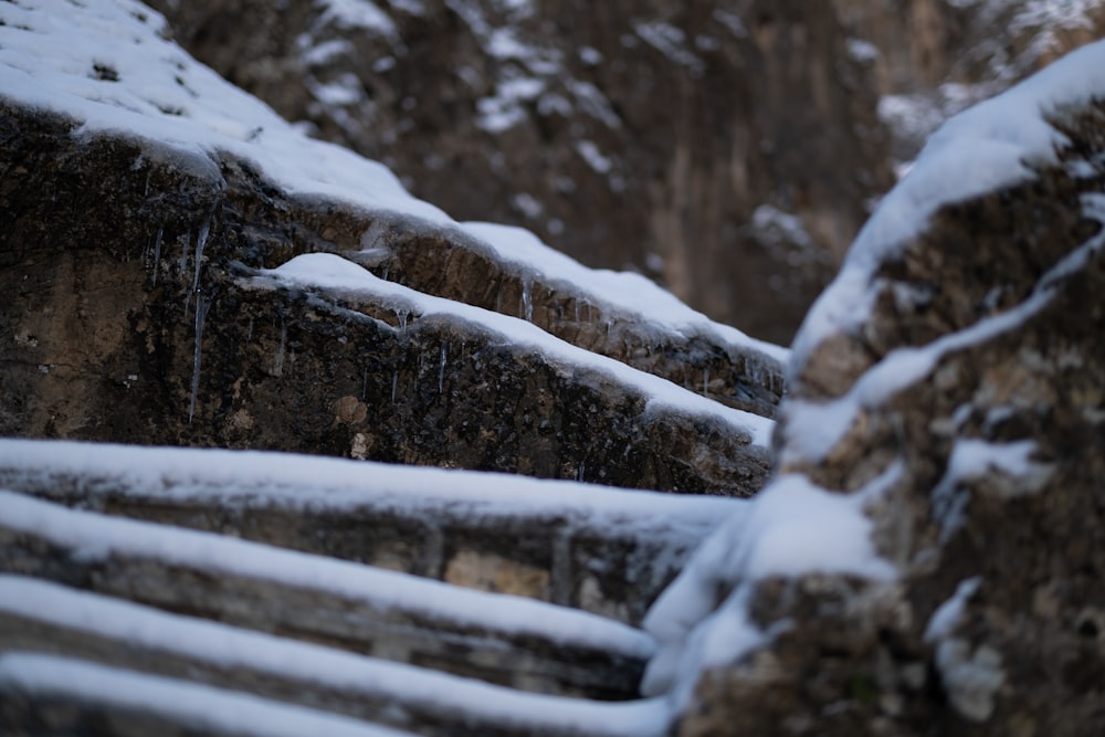 un mur de pierre recouvert de neige à côté d’une falaise