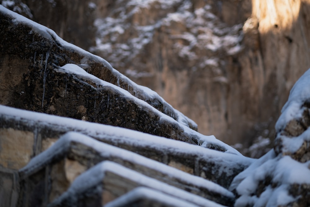 a stone wall covered in snow next to a cliff