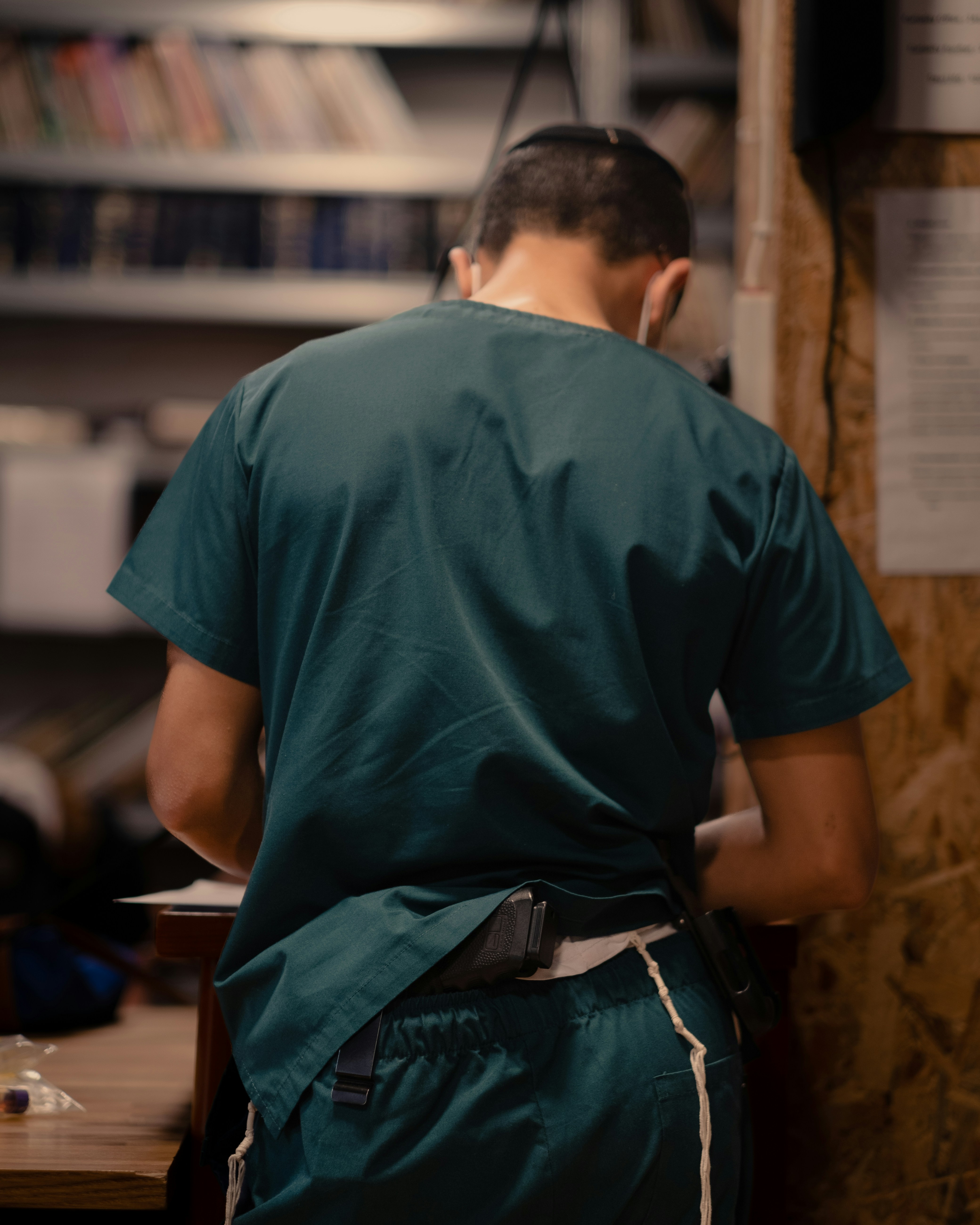 Un uomo con una camicia verde è in piedi davanti a una libreria