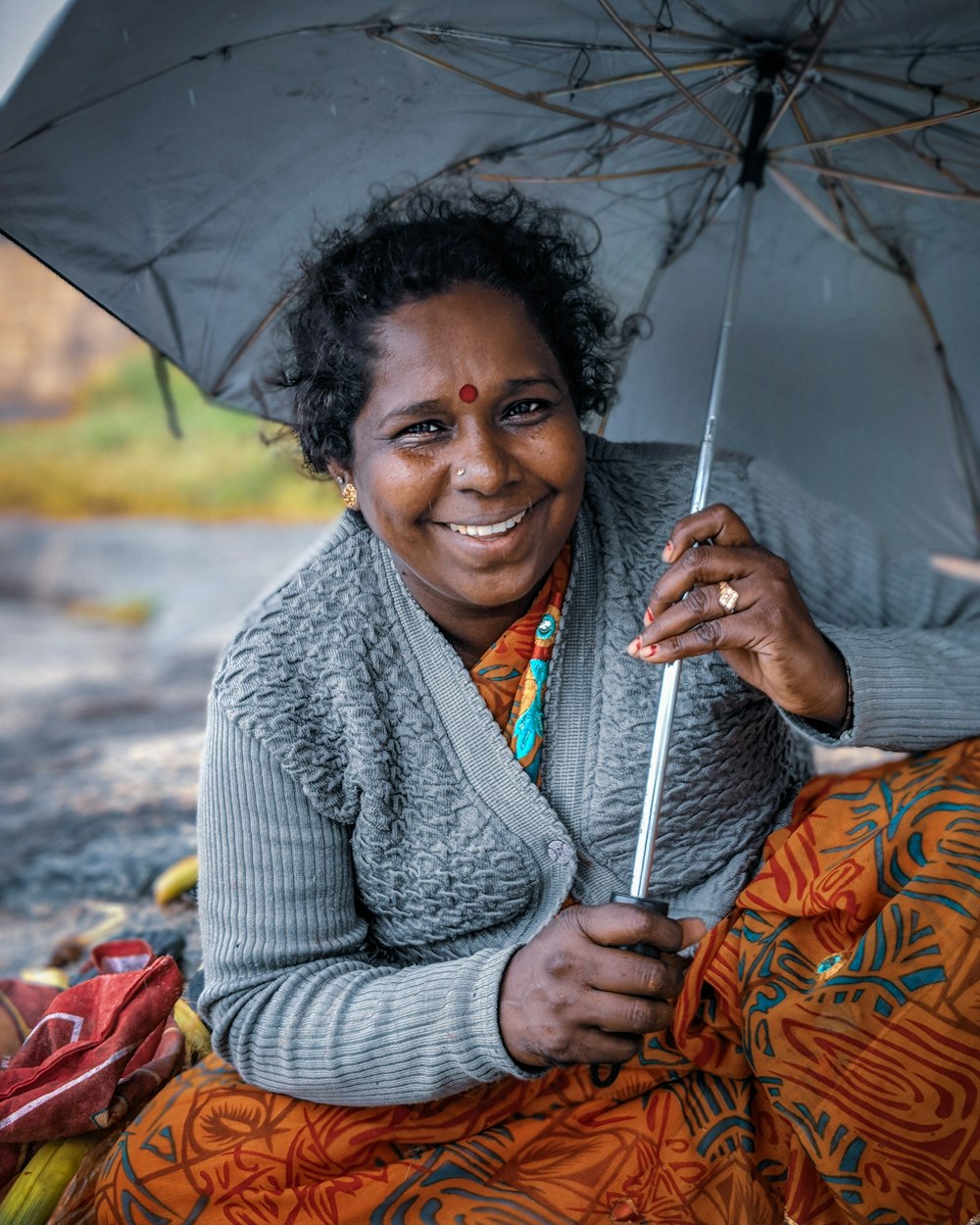 a woman sitting on the ground holding an umbrella