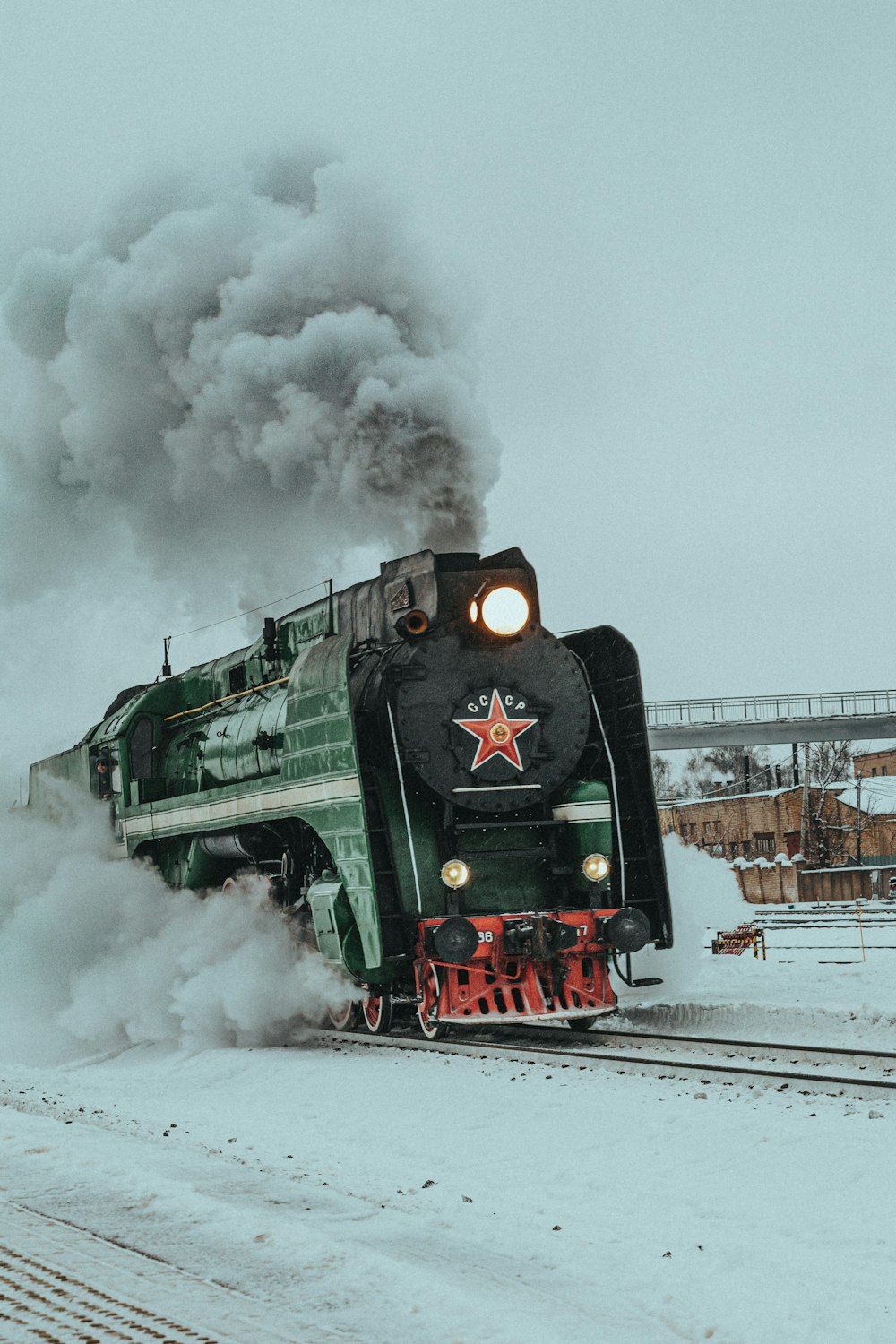 Ein Zug fährt schneebedeckt die Bahngleise hinunter