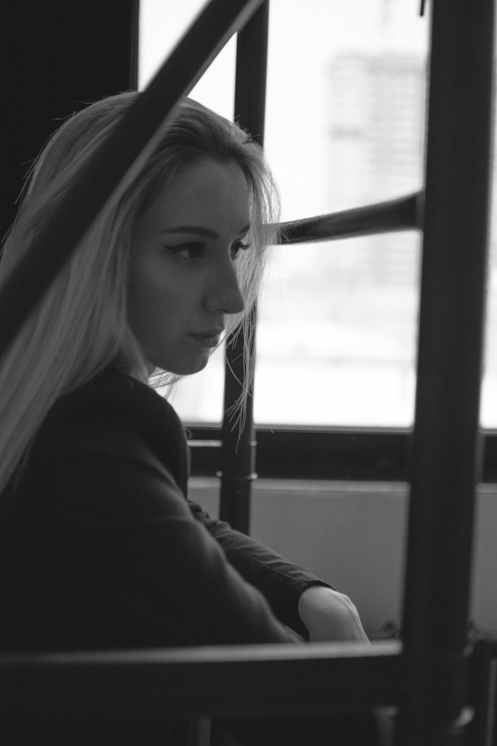 a black and white photo of a woman sitting in a bus