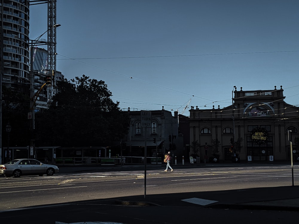 a man walking across a street next to tall buildings