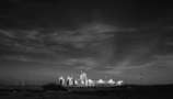 A high-contrast nighttime shot of a landfill gas facility illuminated with green and copper lights against a graphite-black sky.