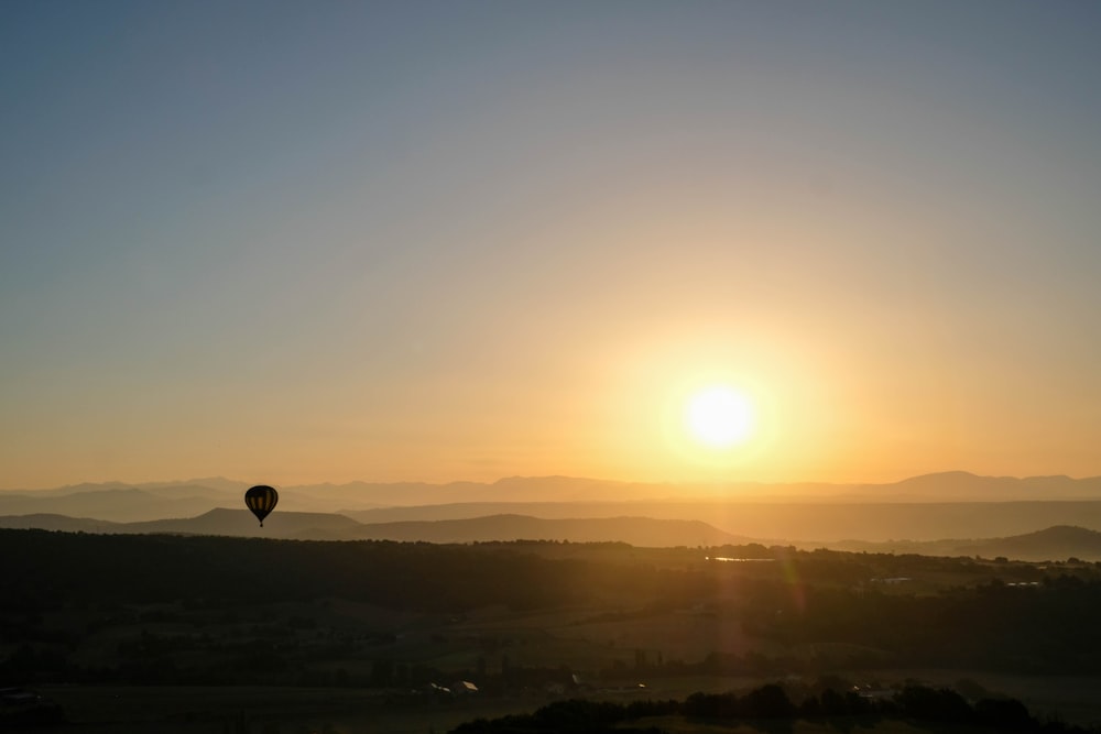 a hot air balloon flying in the sky at sunset