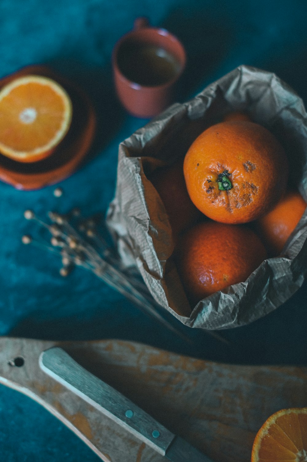 a bowl of oranges and a knife on a table