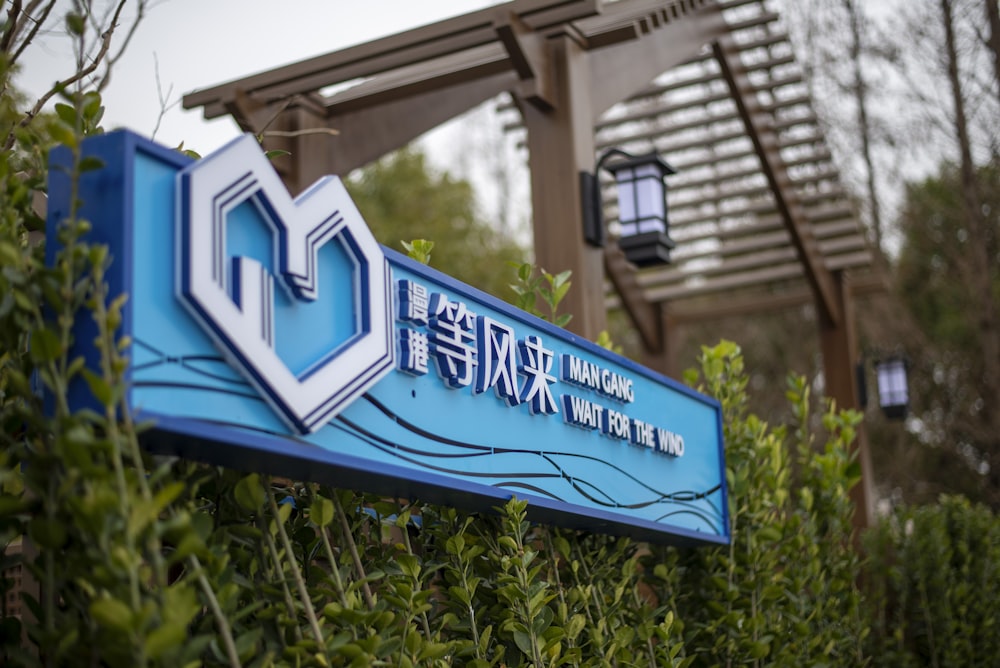 a blue and white sign in front of some bushes