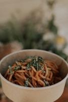 a close up of a bowl of spaghetti with herbs