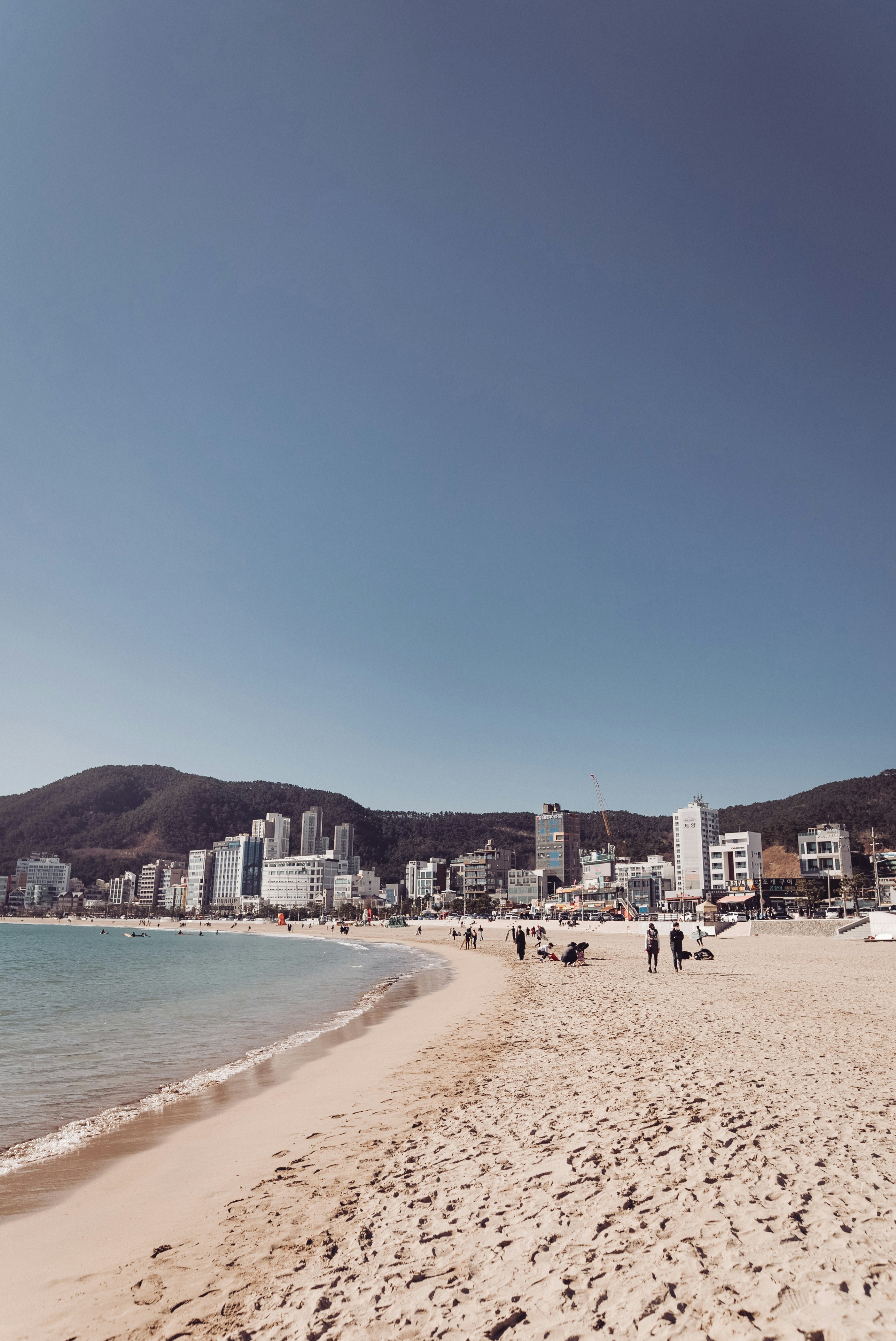 a beach with people walking on it and buildings in the background