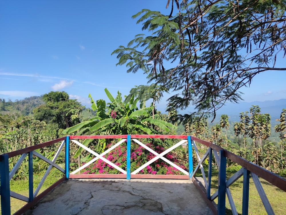 a blue and white railing and some trees and flowers