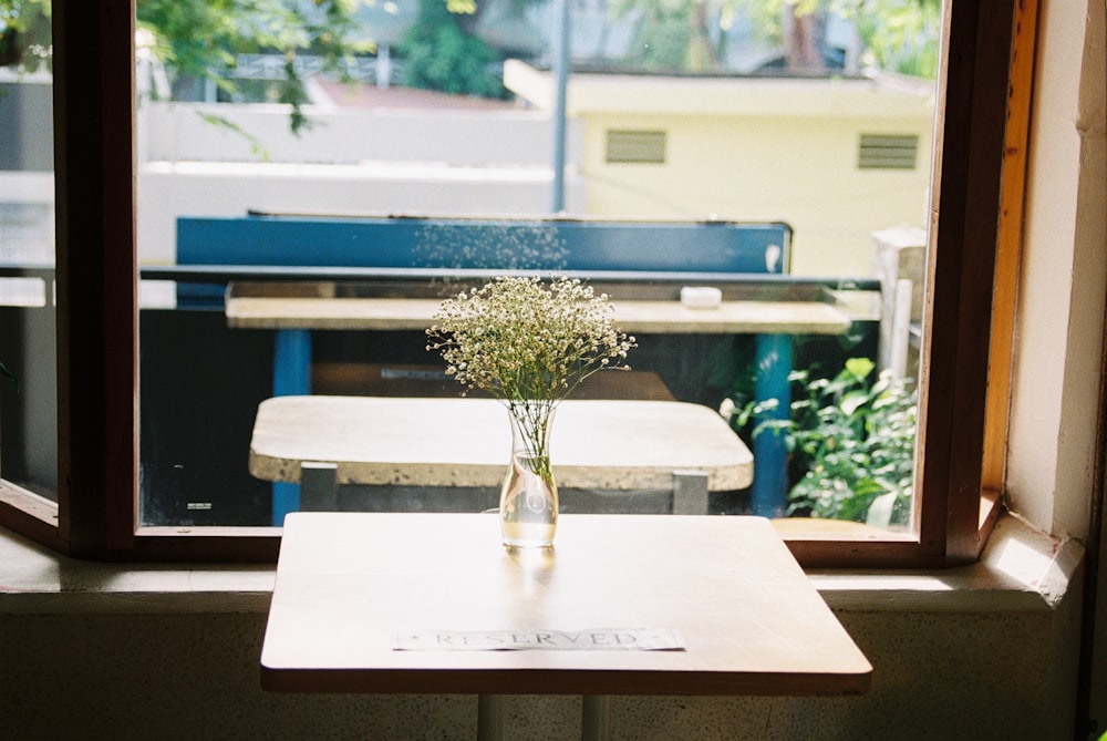 a vase of flowers sitting on a table in front of a window