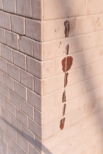 Hand repairing a small chip on a bathroom tile with professional tools.