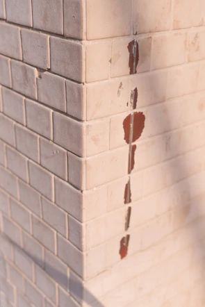 Damaged tile with a visible drill hole before repair in a bathroom setting