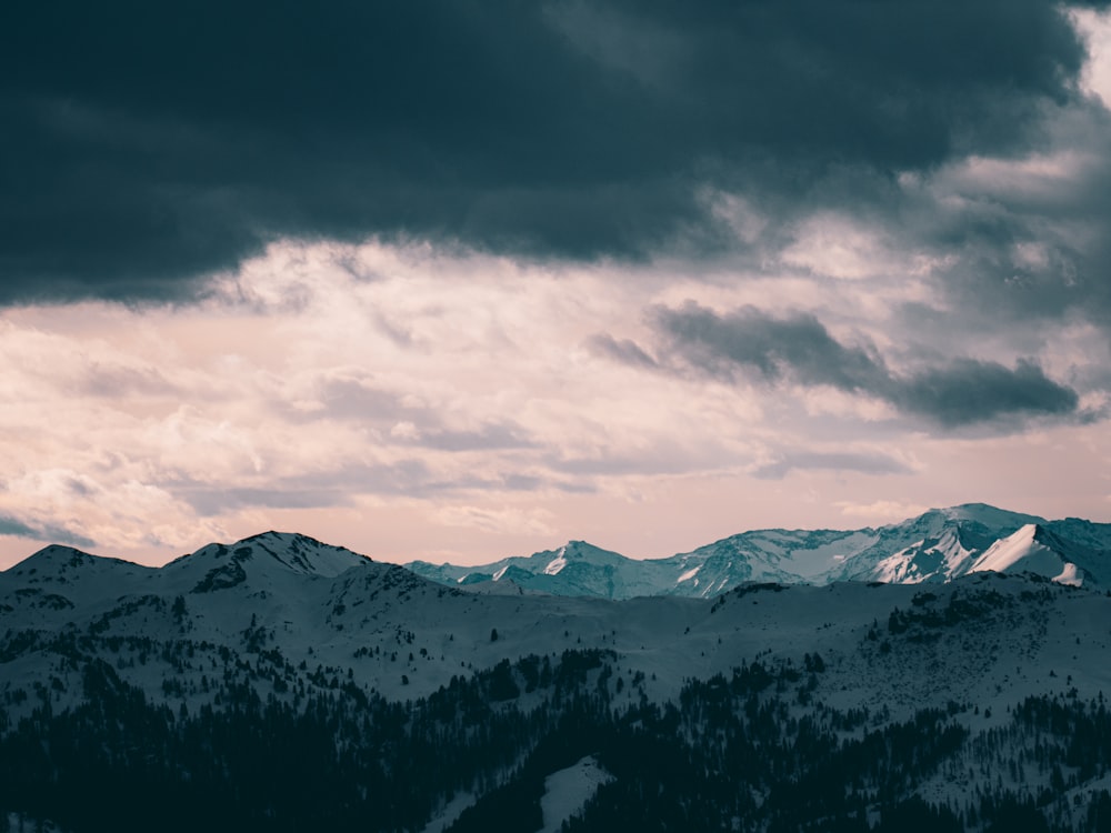 a snowy mountain range under a cloudy sky