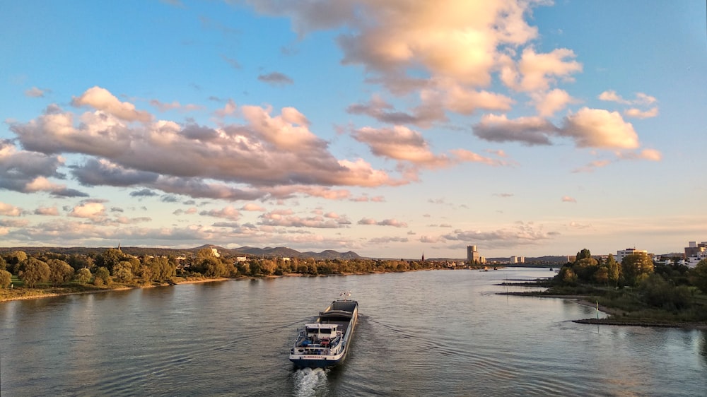 a boat traveling down a river under a cloudy sky