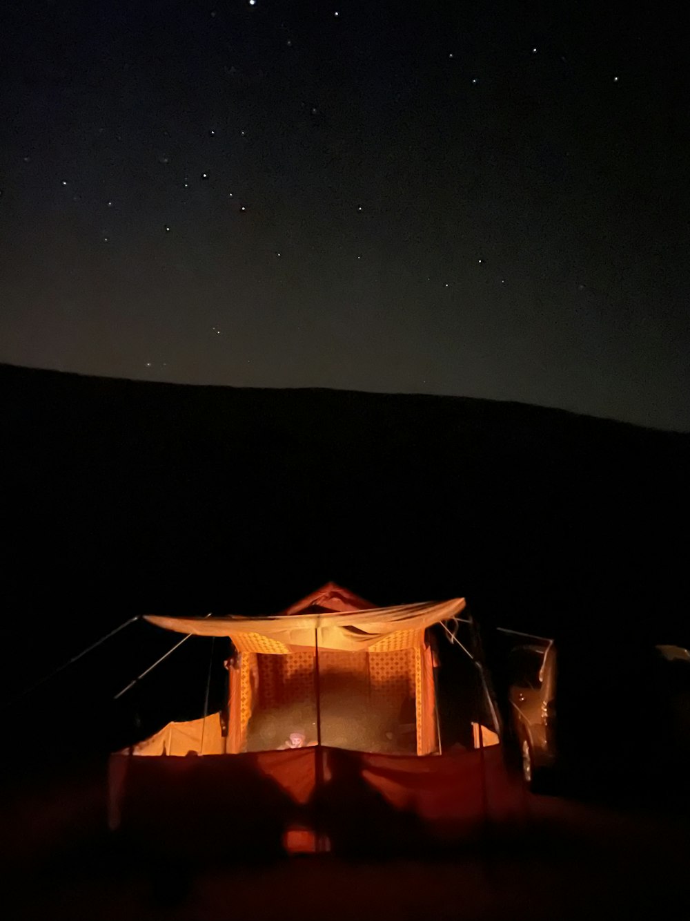a tent is lit up at night with stars in the sky