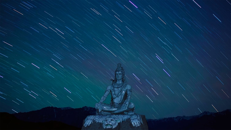 A serene image of a person meditating under a starry sky, surrounded by astrological symbols.