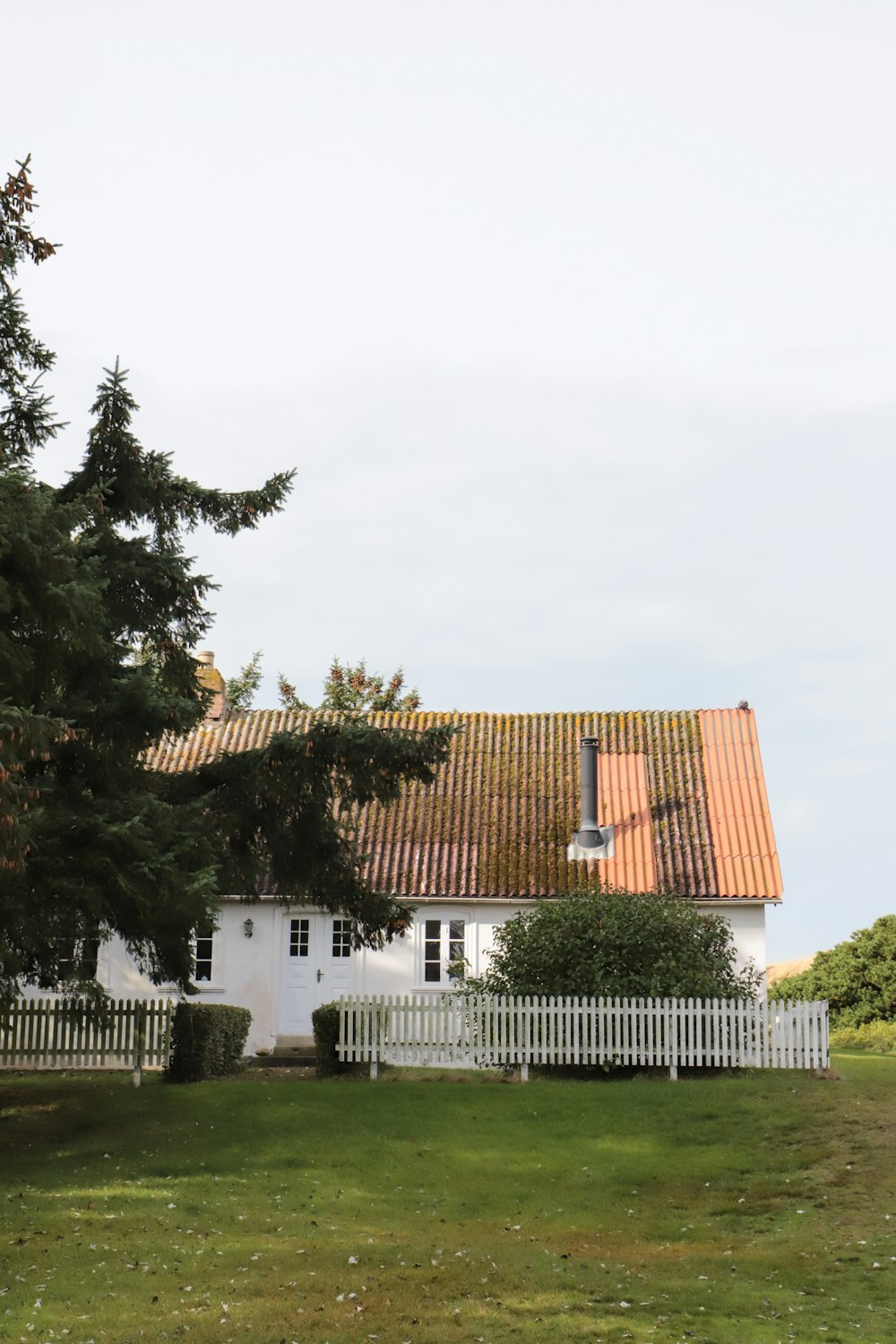 uma casa branca com um telhado de telhas vermelhas