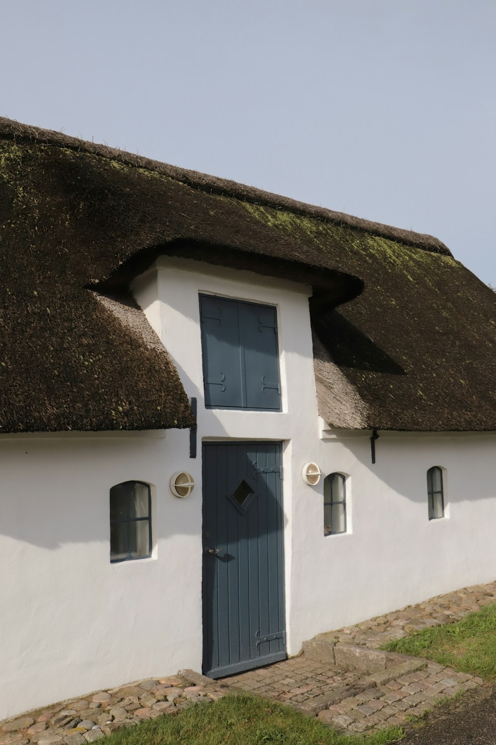 uma casa branca com um telhado de palha e uma porta azul