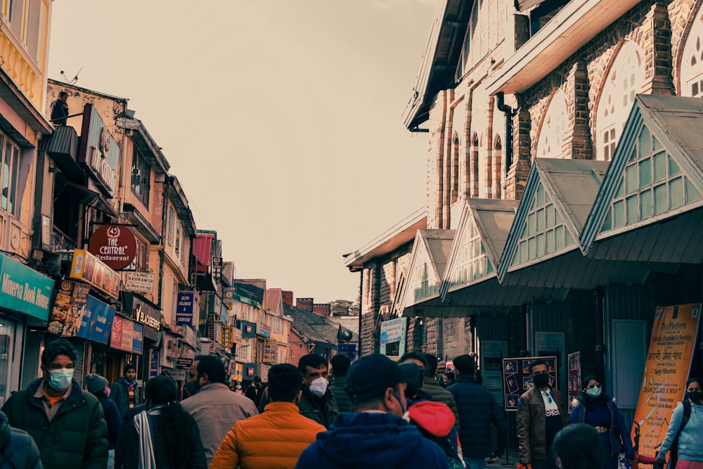 a crowd of people walking down a street next to tall buildings