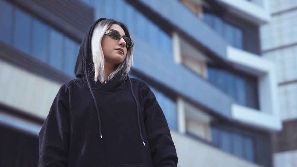 a woman with white hair and sunglasses standing in front of a building