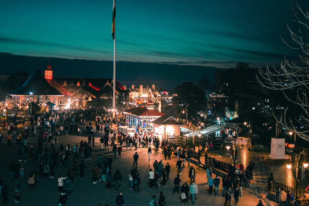 a crowd of people standing around a carnival at night