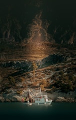 A fishing trawler anchored near a coastal village at dawn.