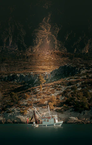 A sturdy fishing boat anchored near a sandy shore at sunrise, ready for a day on the water.