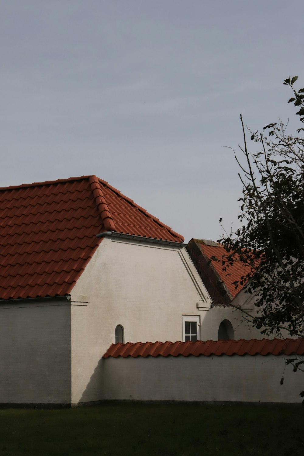 a white house with a red roof and a tree