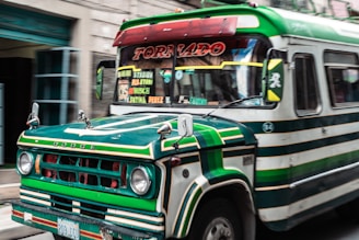 a green and white bus driving down a street