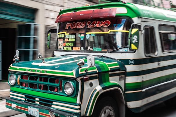 a green and white bus driving down a street