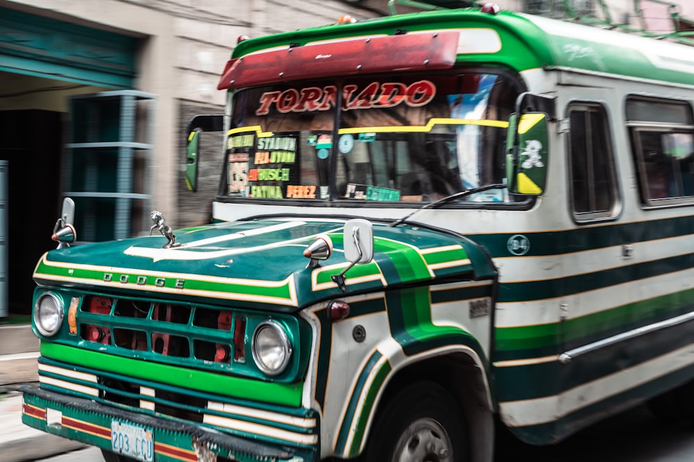 a green and white bus driving down a street