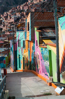 A local host warmly welcoming a visitor into a vibrant Medellín neighborhood filled with colorful street art.