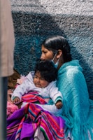 a woman and child are sitting against a wall