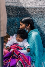 a woman and child are sitting against a wall