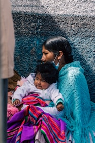 a woman and child are sitting against a wall