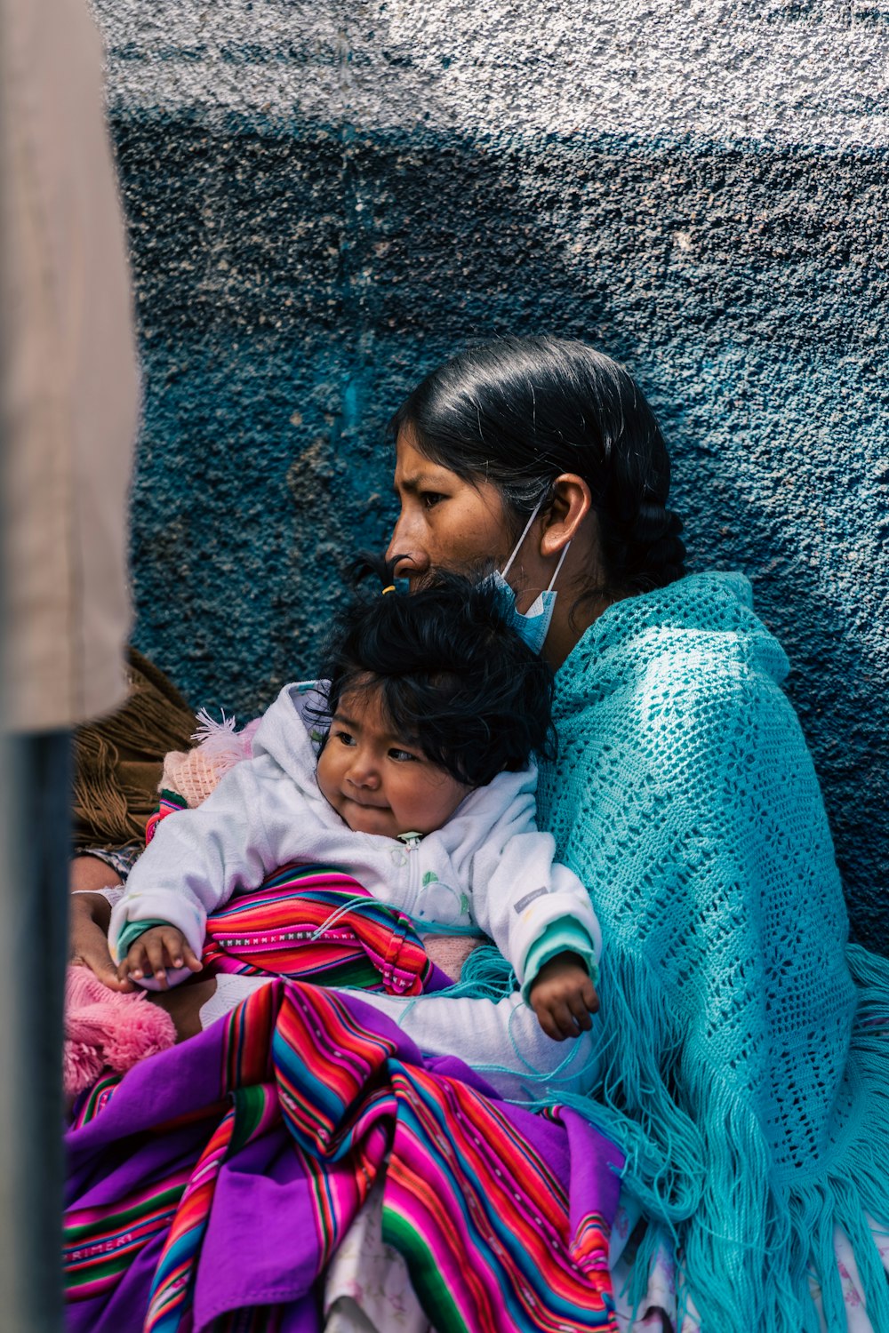 a woman and child are sitting against a wall