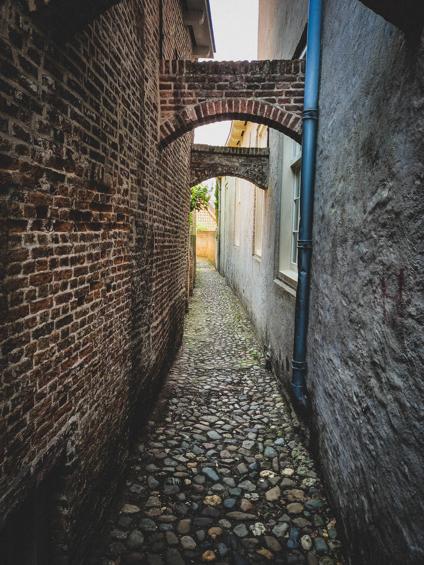 A narrow cobblestone street with a brick archway