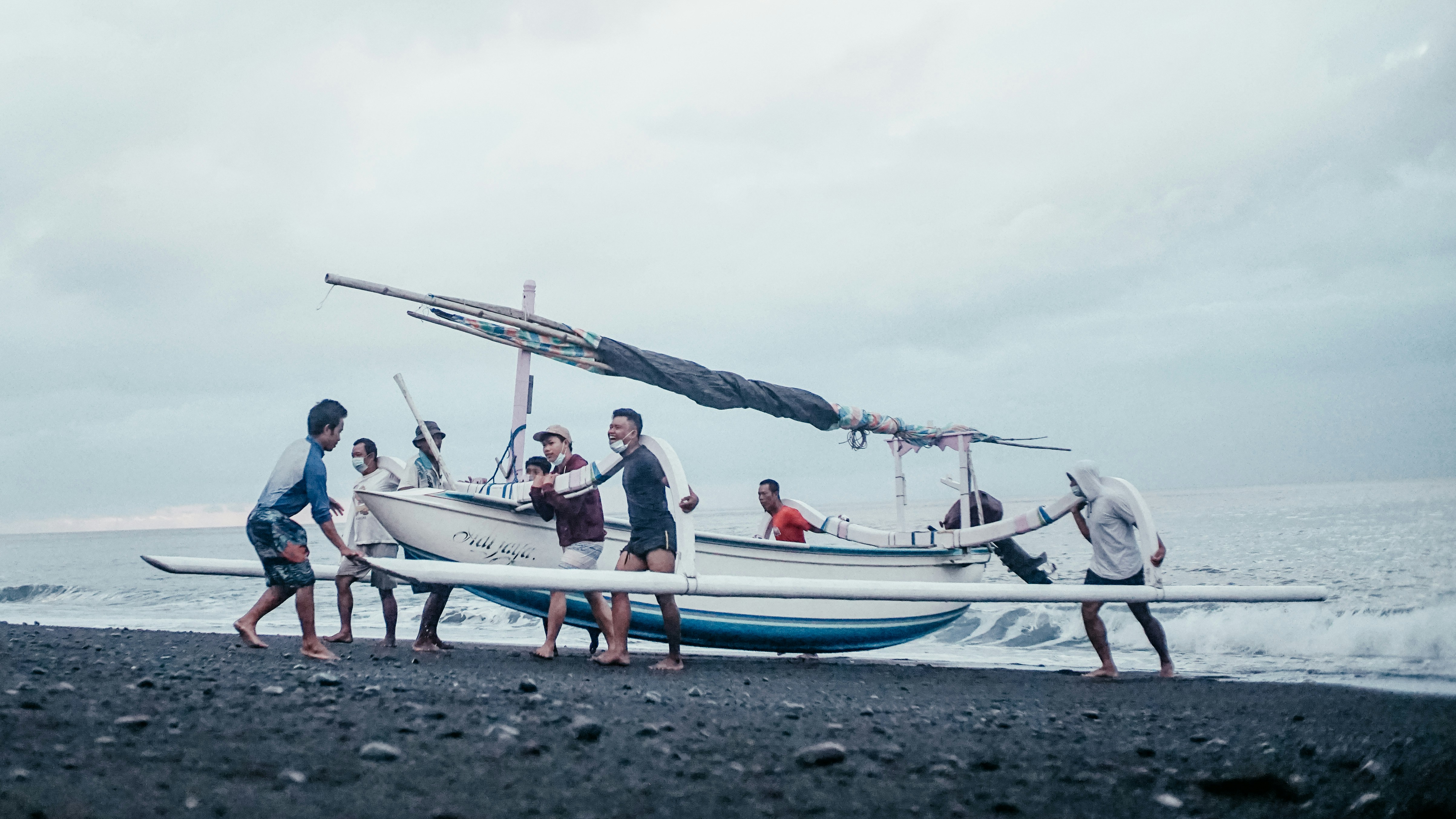 a group of people standing on top of a beach next to a boat