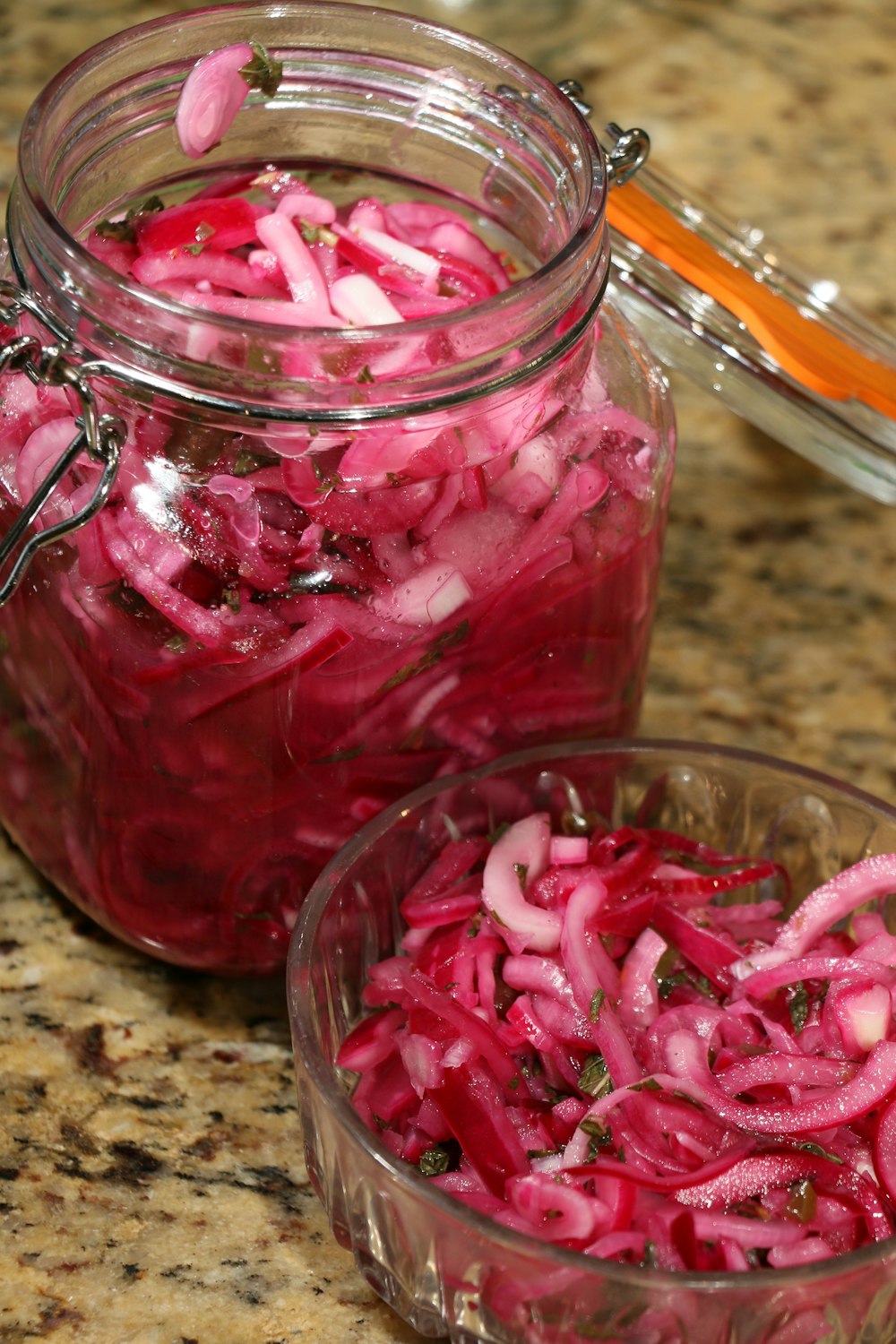 a glass jar filled with red onions on top of a counter