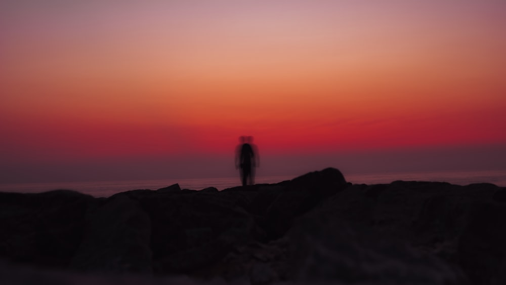 a person standing on a rocky beach at sunset