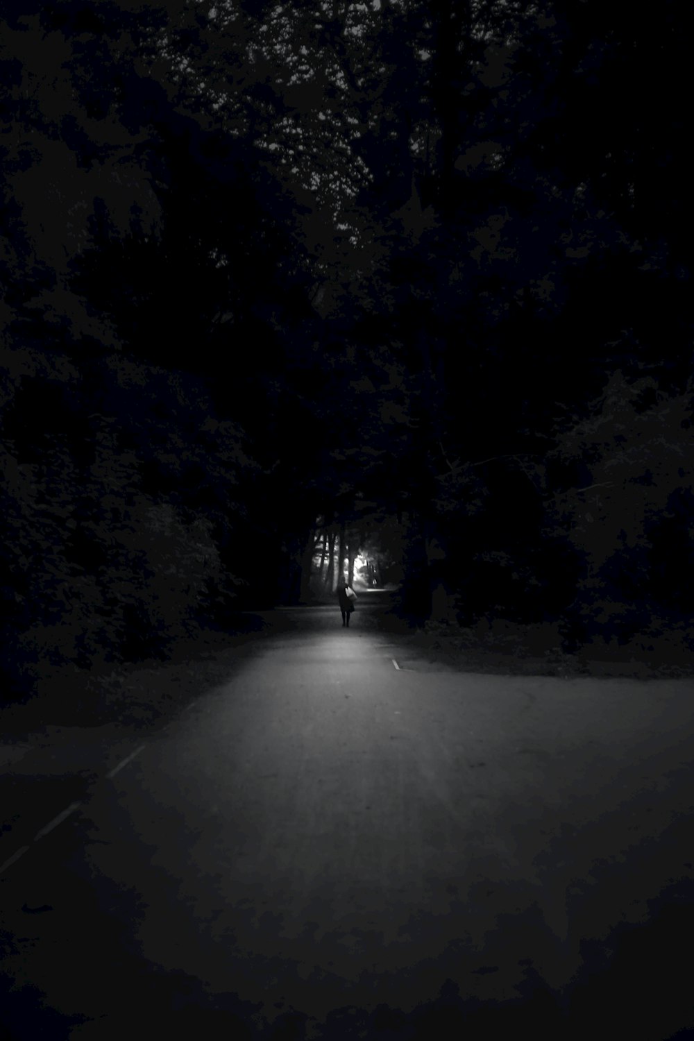 a person walking down a dark road at night