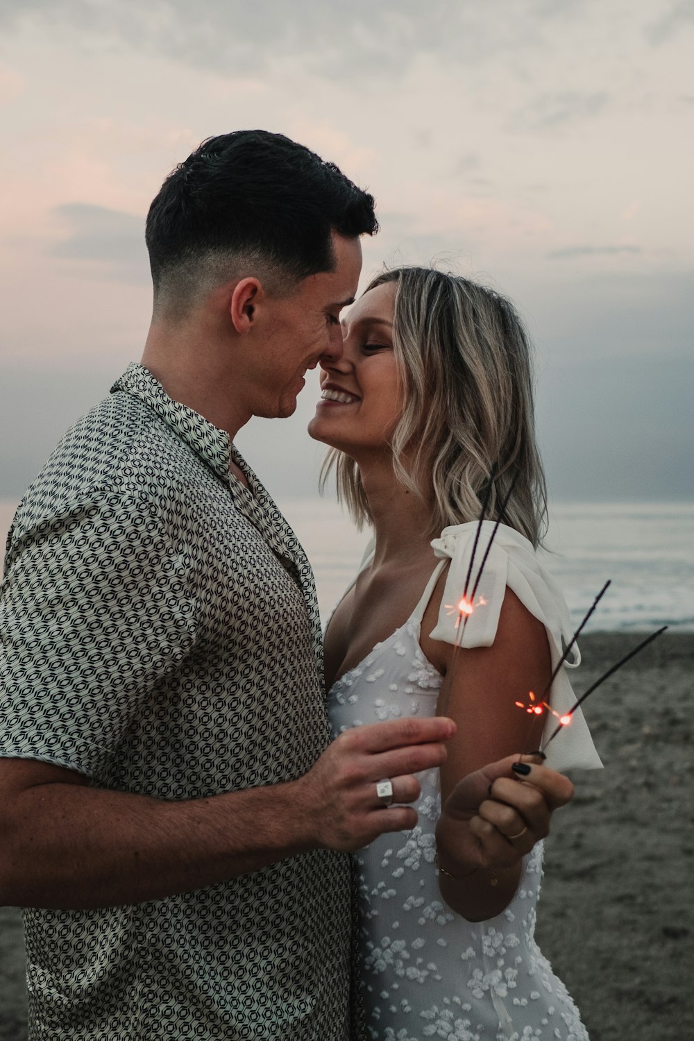 a man and a woman standing next to each other on a beach