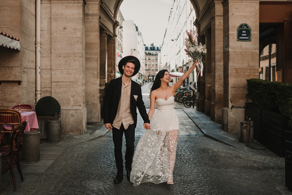 a man and woman walking down a street holding hands