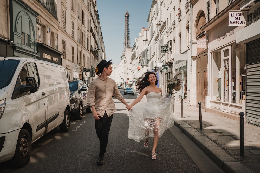 a man and woman walking down a street holding hands