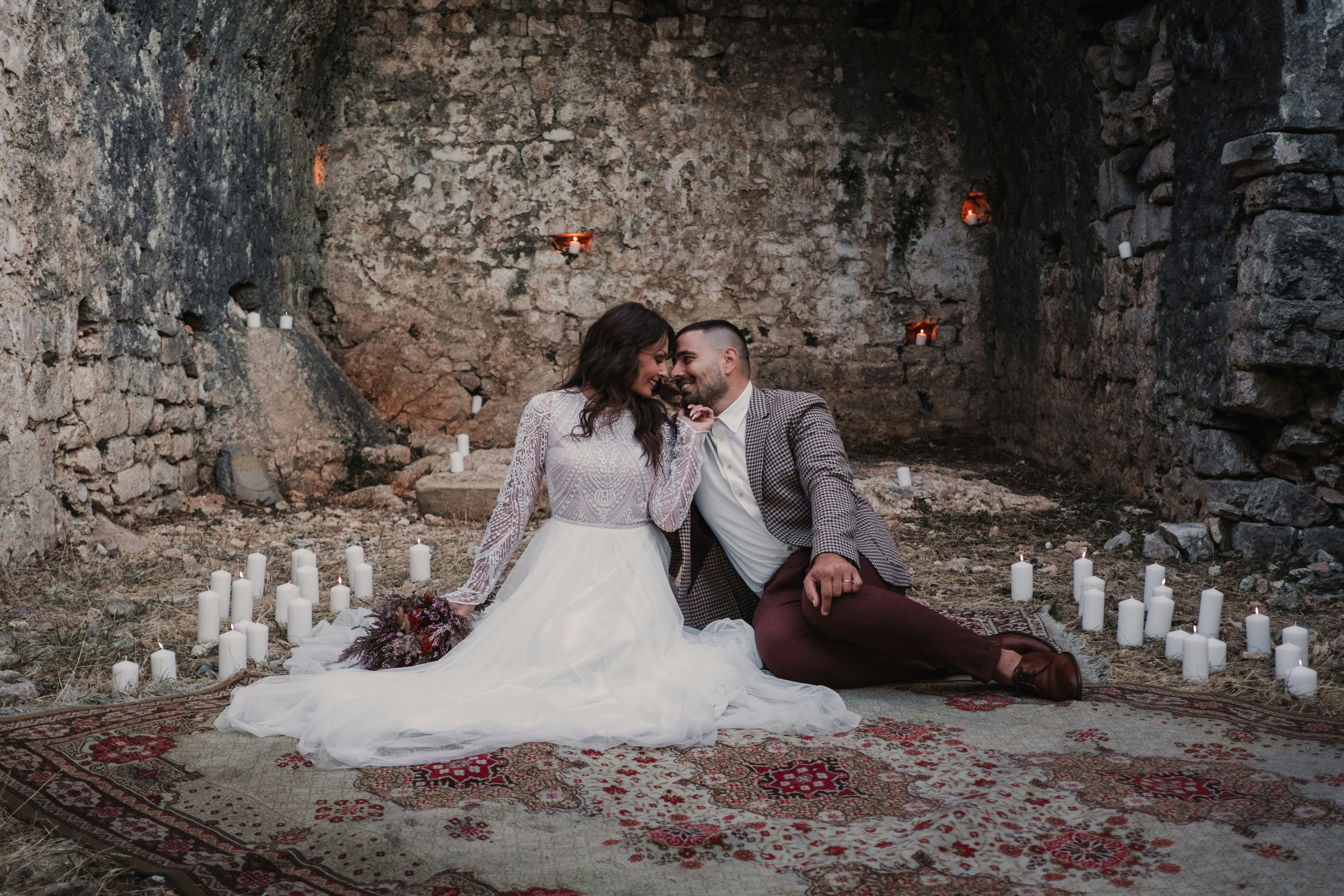 a bride and groom sitting on a rug in an old castle