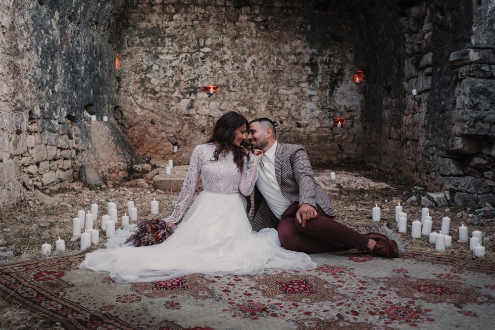 a bride and groom sitting on a rug in an old castle