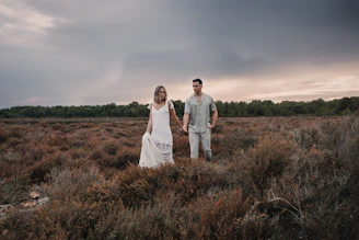 a man and a woman holding hands in a field