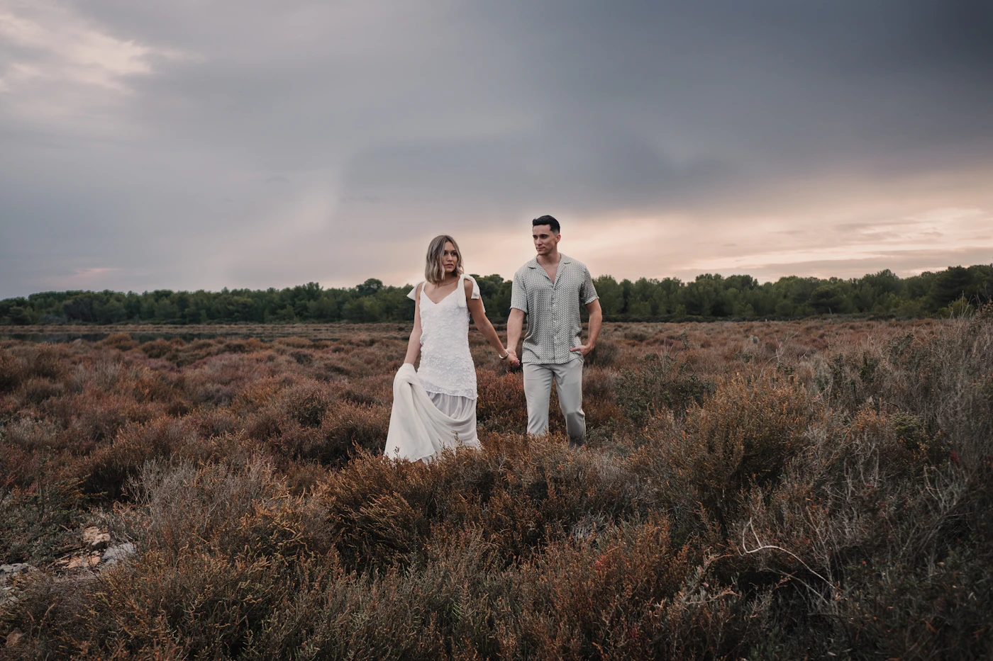 Couple walking through autumn-coloured lenga beech forest in Argentine Patagonia during their elopement with the dramatic peaks visible through the trees