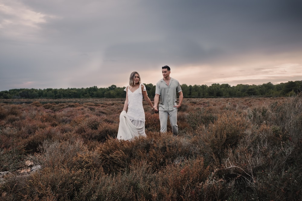 a man and a woman holding hands in a field